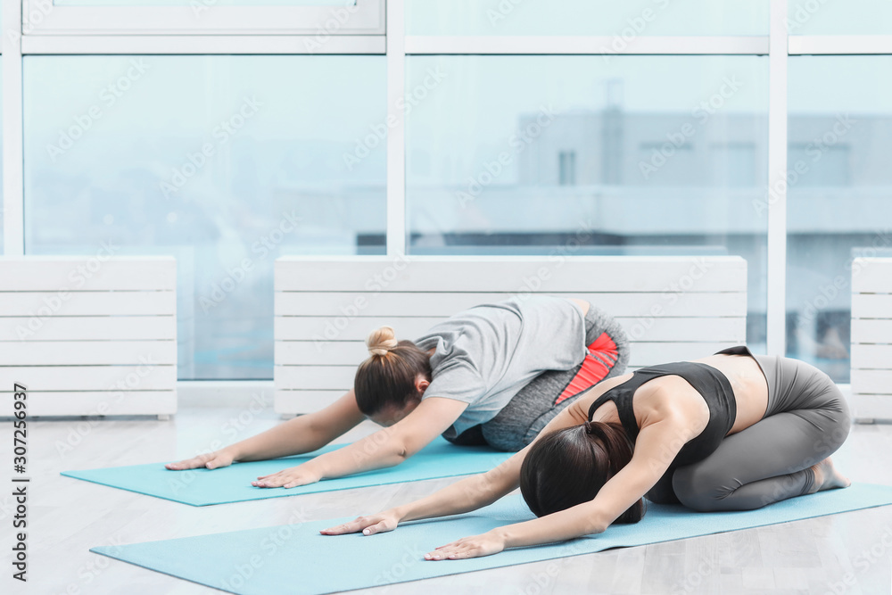 Sporty young women practicing yoga in gym