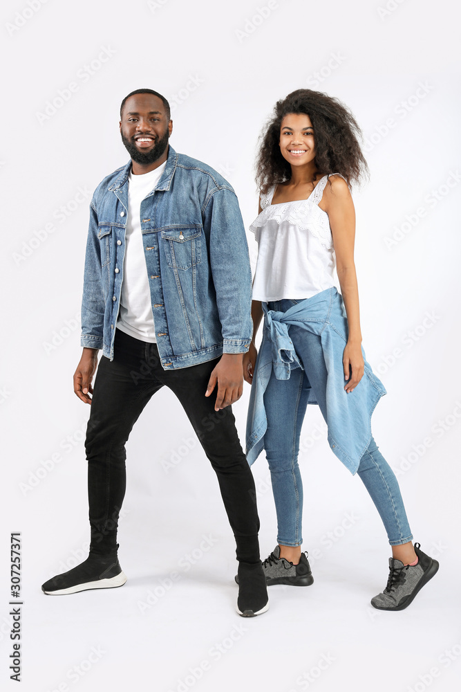 Portrait of stylish young African-American couple on white background