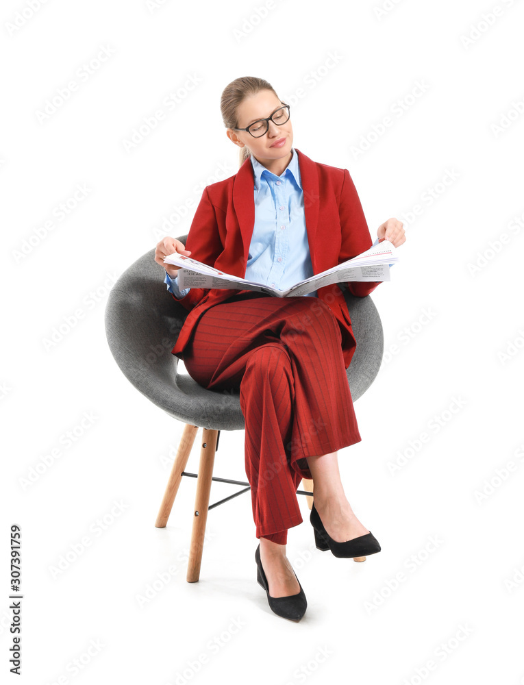 Young businesswoman with newspaper sitting in armchair against white background