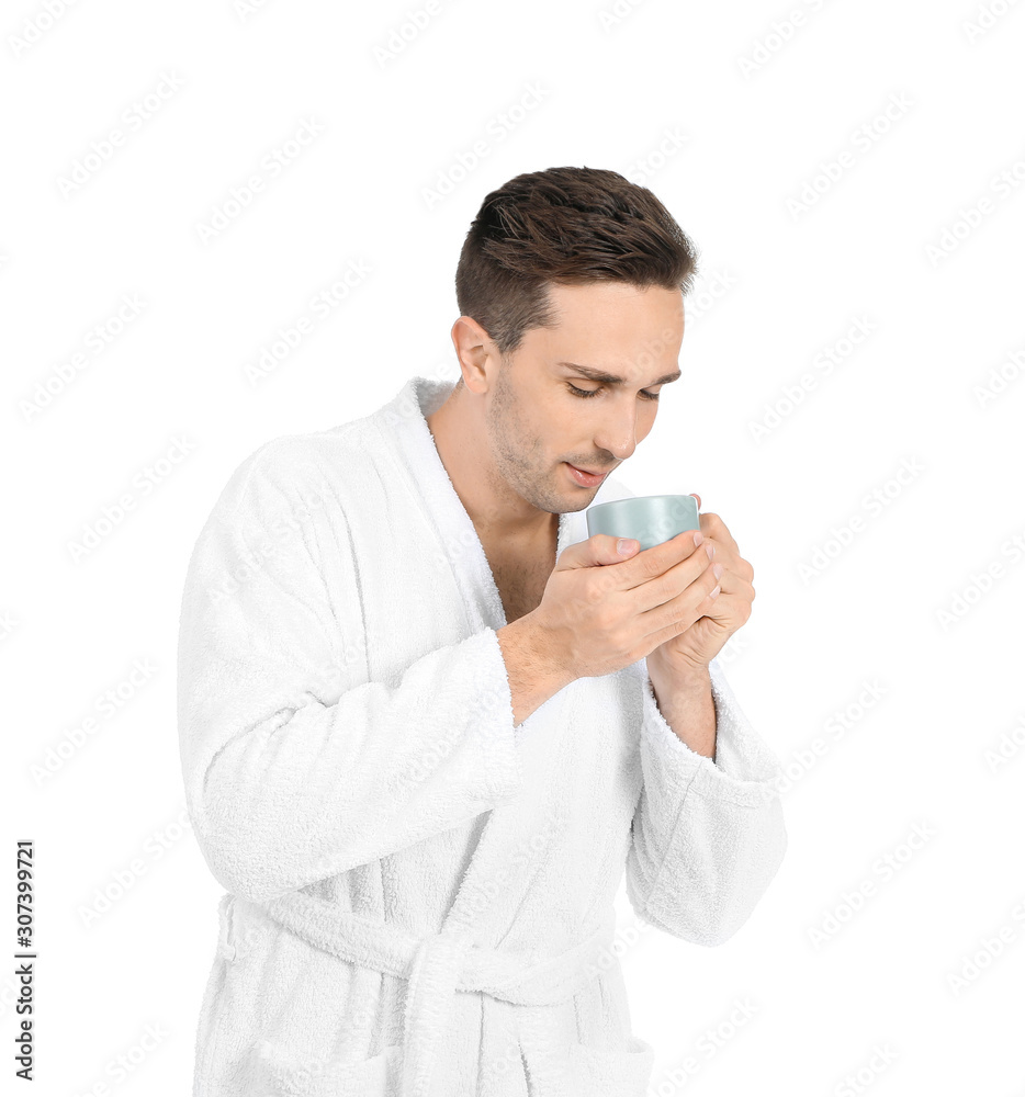 Handsome man in bathrobe and with cup of coffee on white background