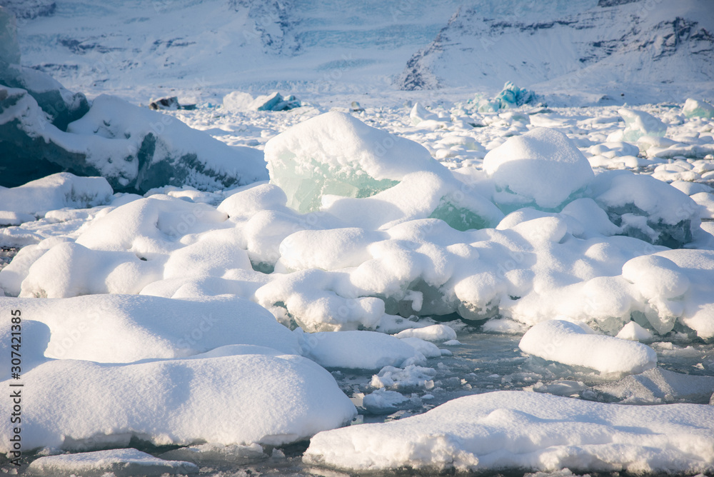 Glacier ice floating on the water with snow at Jokulsarlon glacier lagoon in the winter time in Icel