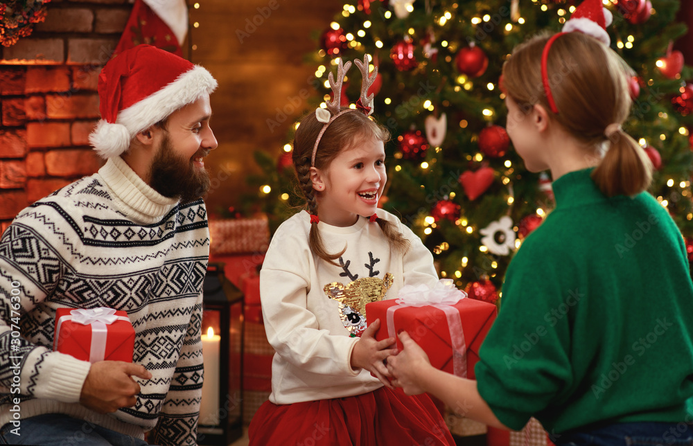 happy family mother, father and child  with gifts near   Christmas tree at home