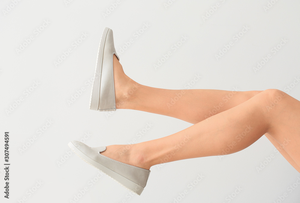 Young woman in stylish shoes on light background