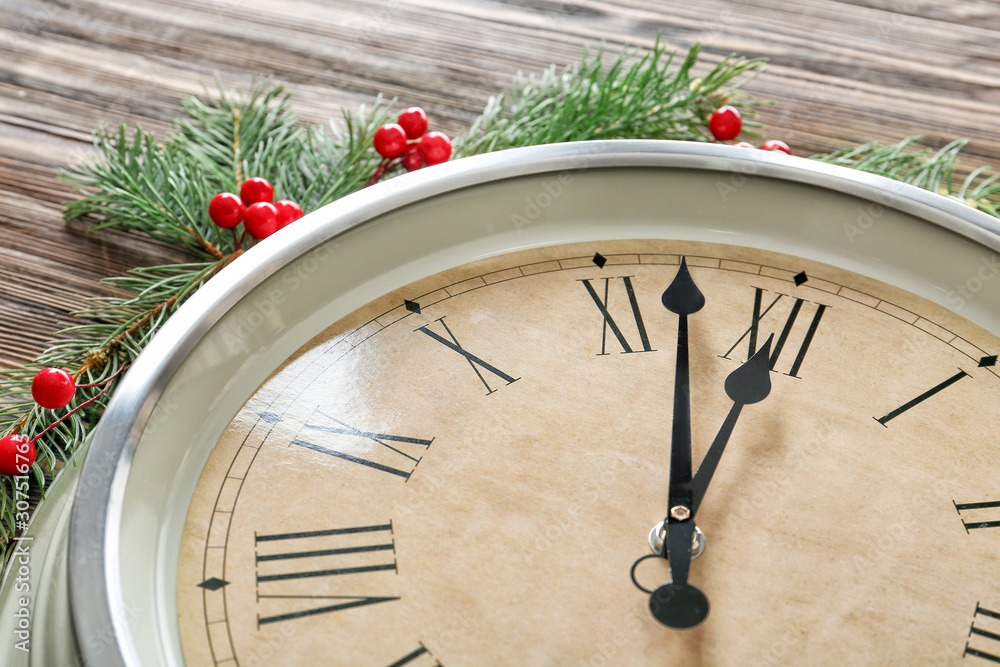 Clock and fir branches on wooden background, closeup. Christmas countdown concept