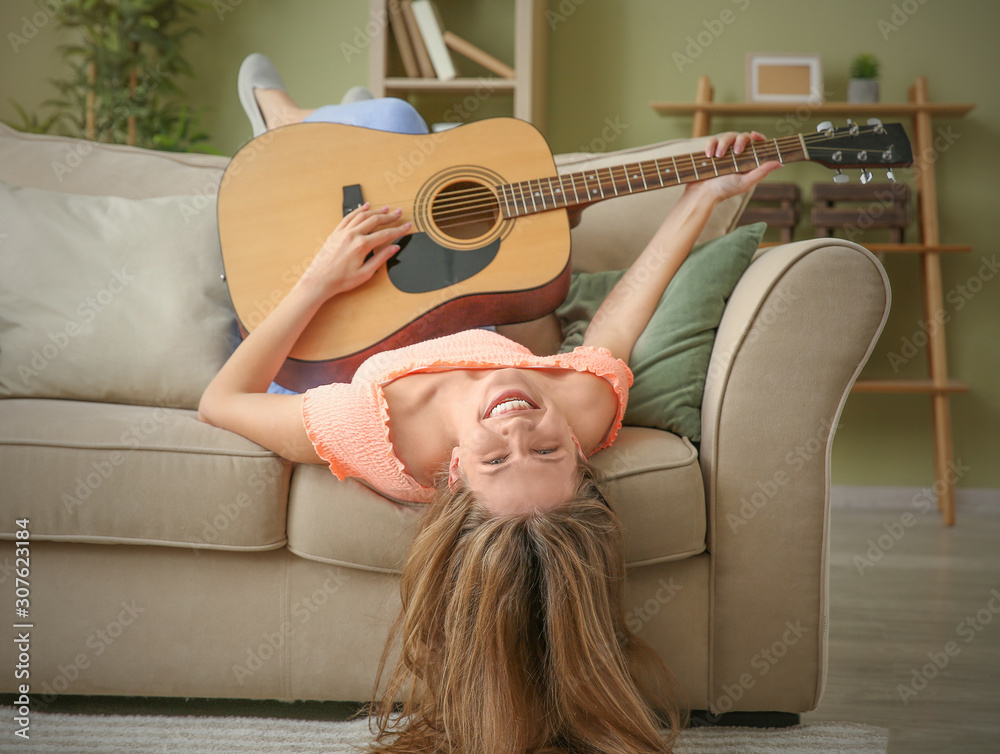 Beautiful young woman with guitar at home