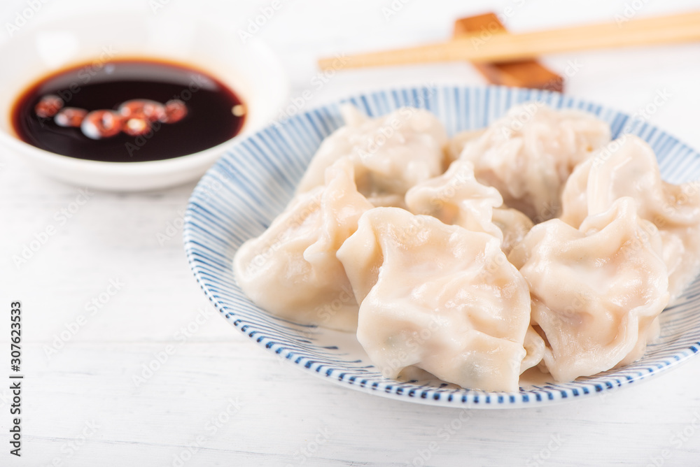 Fresh, delicious boiled pork gyoza dumplings, jiaozi on white background with soy sauce and chopstic