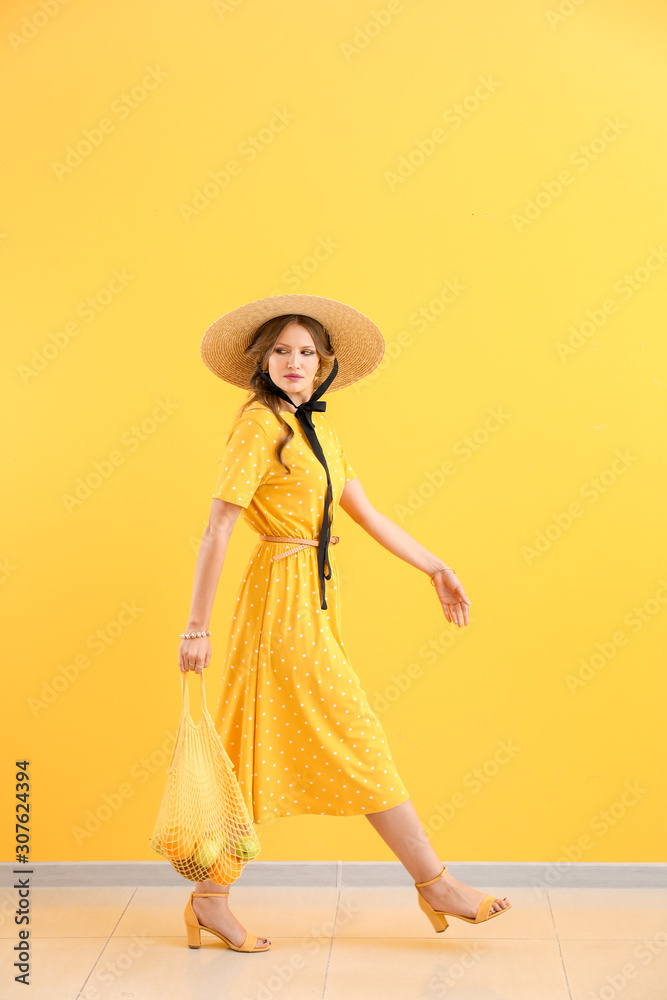 Fashionable young woman against color wall