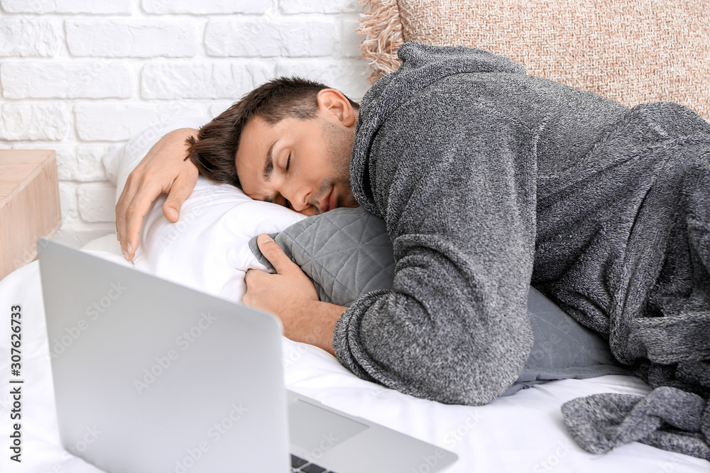 Handsome man in bathrobe sleeping on bed