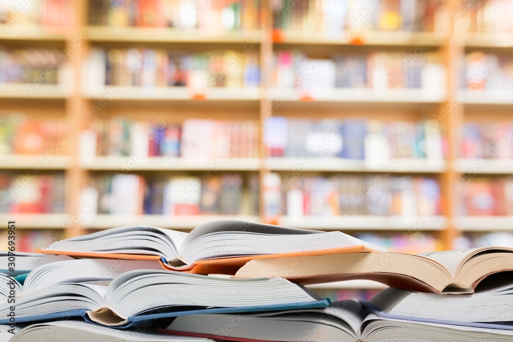 Many open books lying flat before a blue background with various formulas and letters.