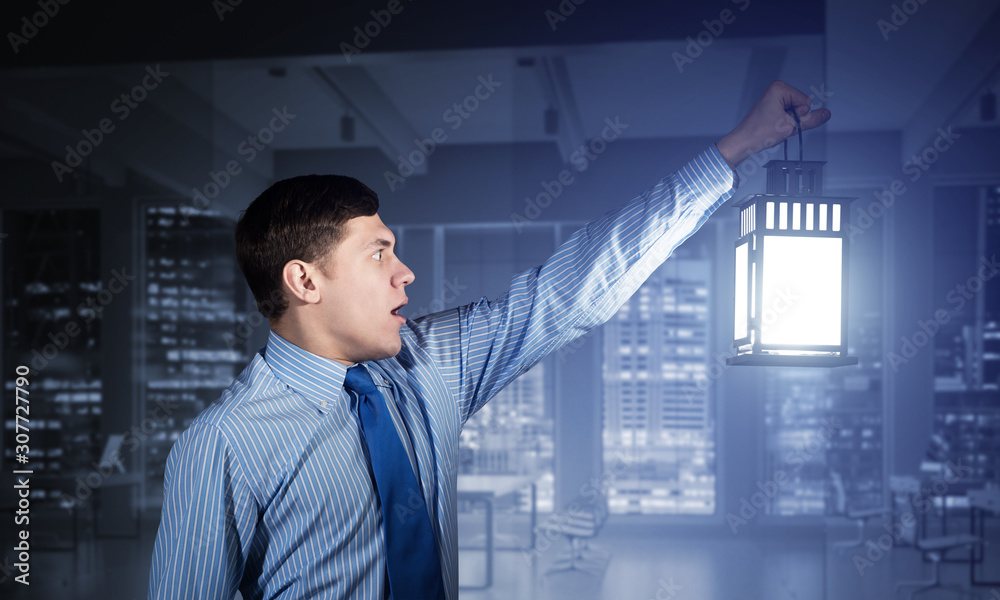 Scared businessman holding glowing lantern