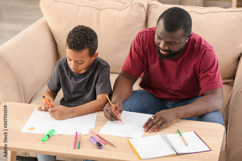 Portrait of African-American man and his little son drawing at home