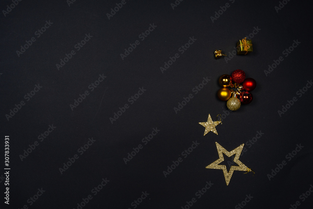 Christmas ornaments (Christmas baubles, stars and little presents) on black background