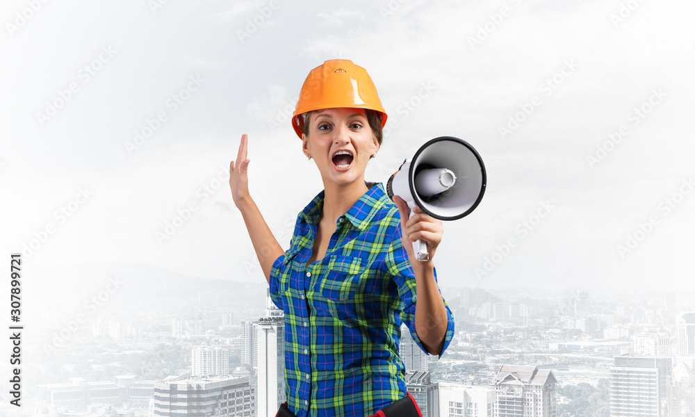 Expressive woman in helmet shouting into megaphone