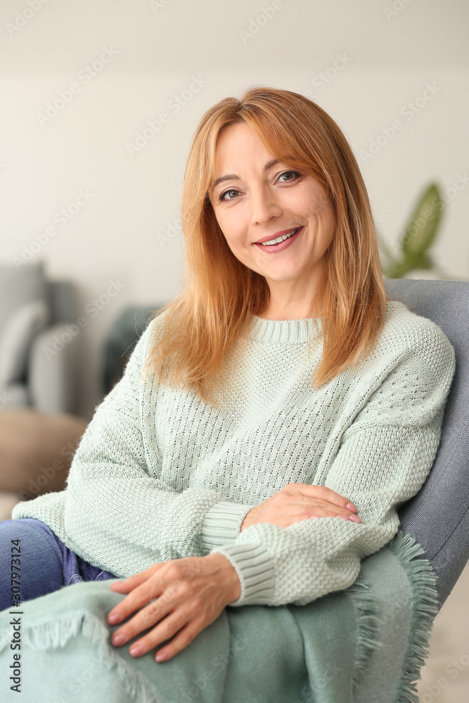 美丽的成熟女人坐在家里的扶手椅上