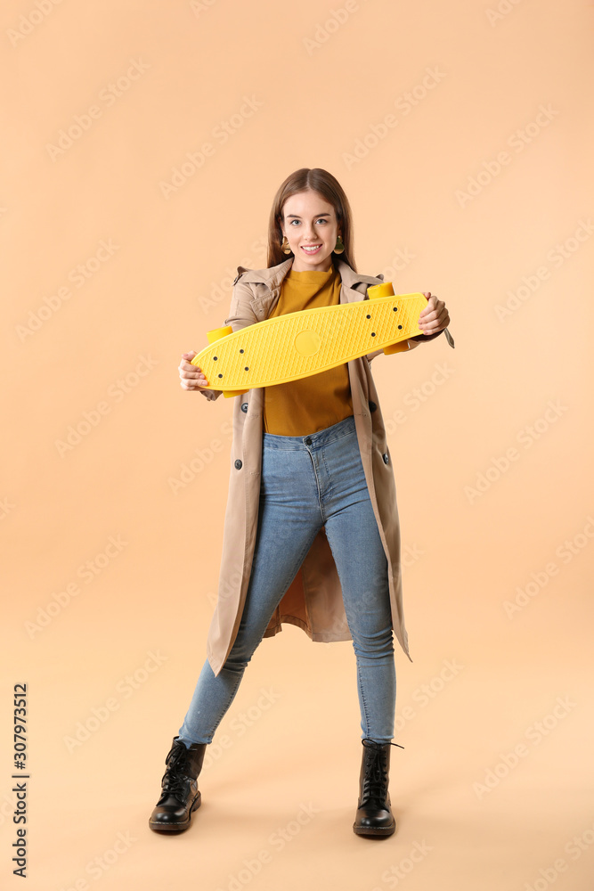 Stylish hipster girl with skateboard on color background