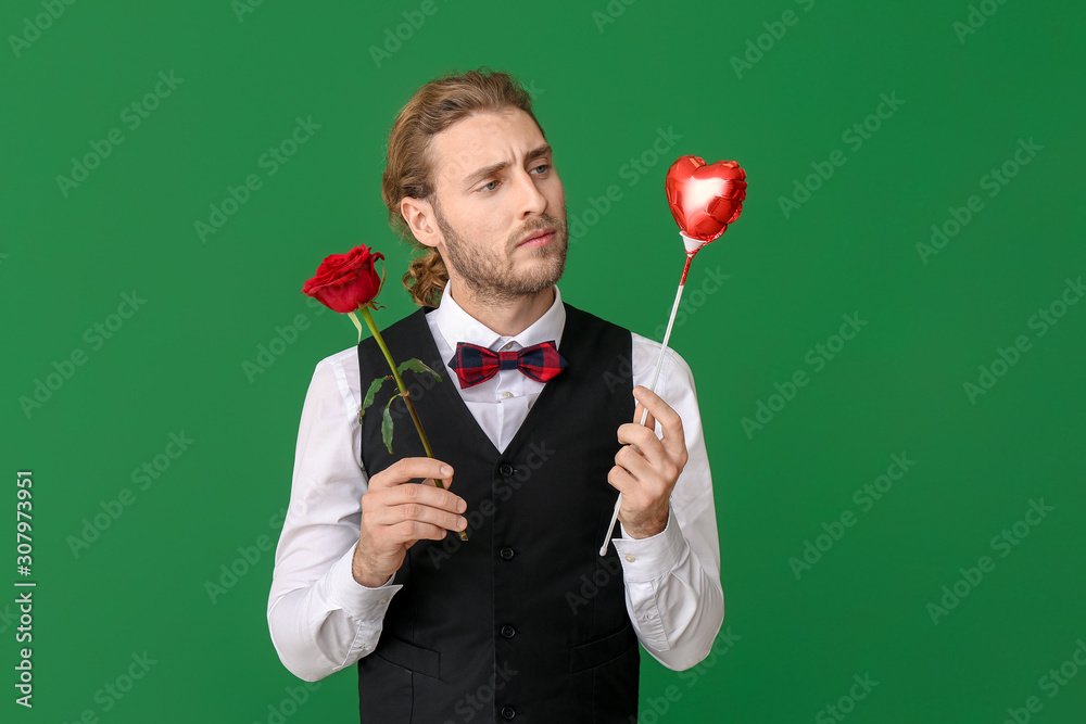 Handsome man with heart and flower on color background. Valentines Day celebration