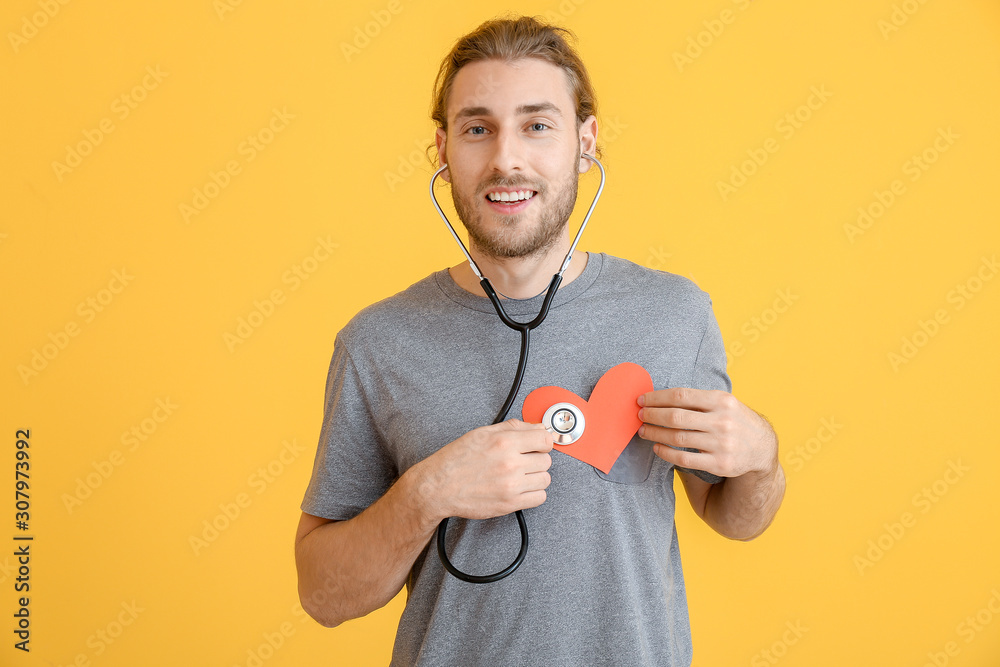 Handsome man with heart and stethoscope on color background. Valentines Day celebration