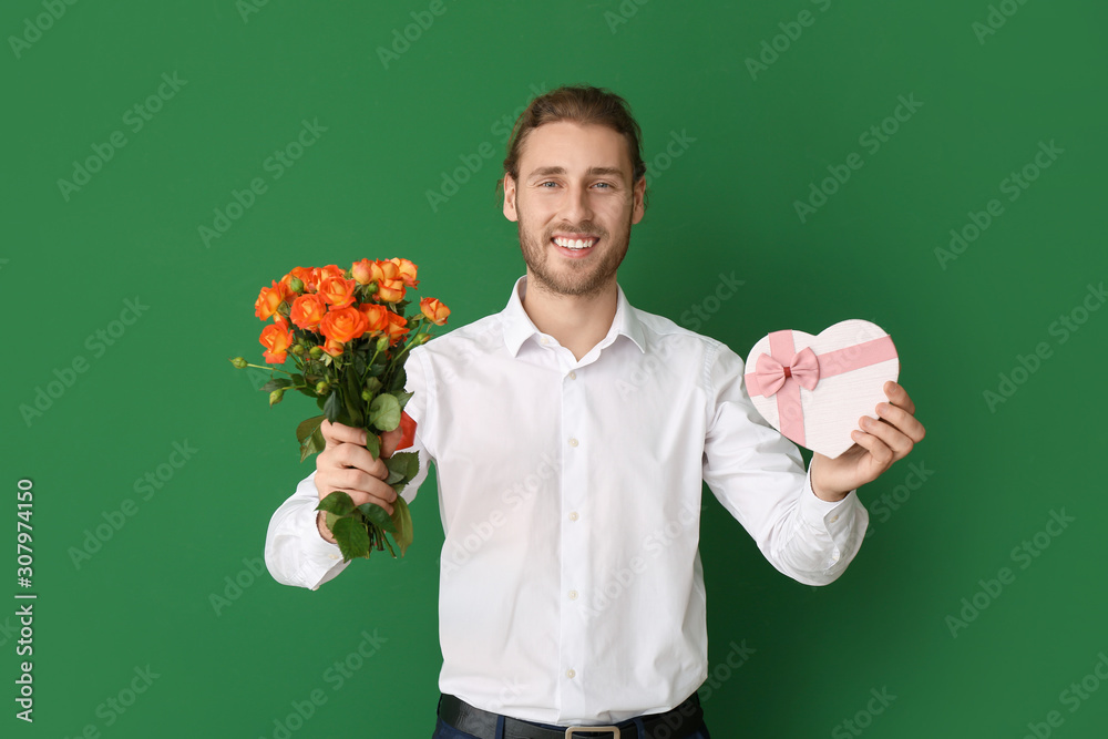 Handsome man with flowers and gift on color background. Valentines Day celebration