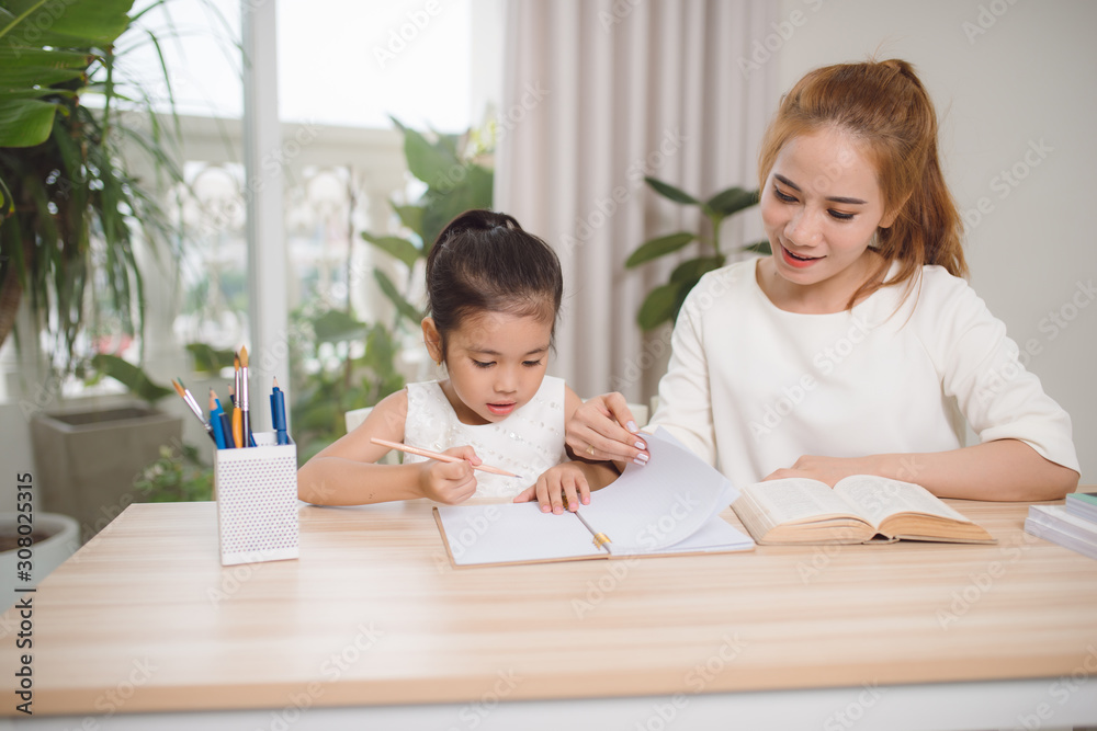 Mother helping her little child with homework