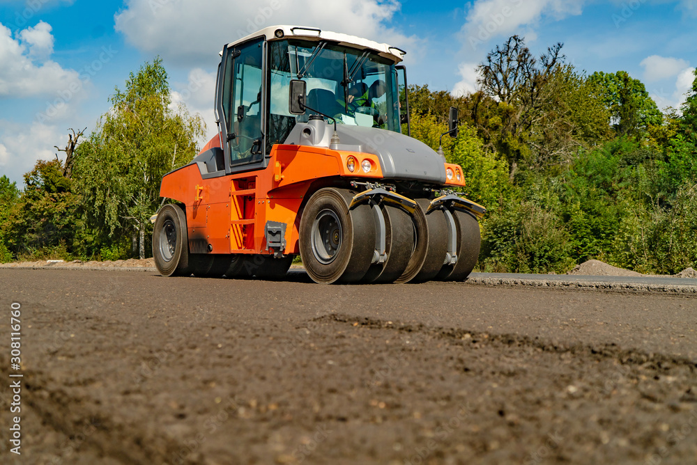 Tandem vibration roller compactor working on asphalt pavement, selective focus on road repair.