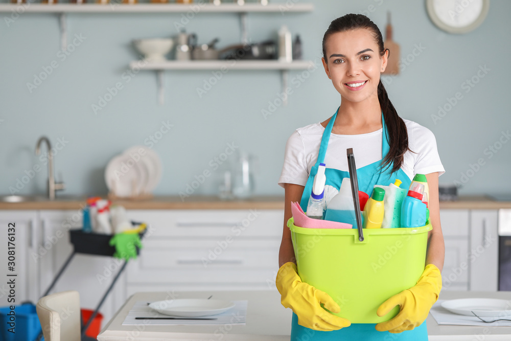 Female janitor with cleaning supplies in kitchen