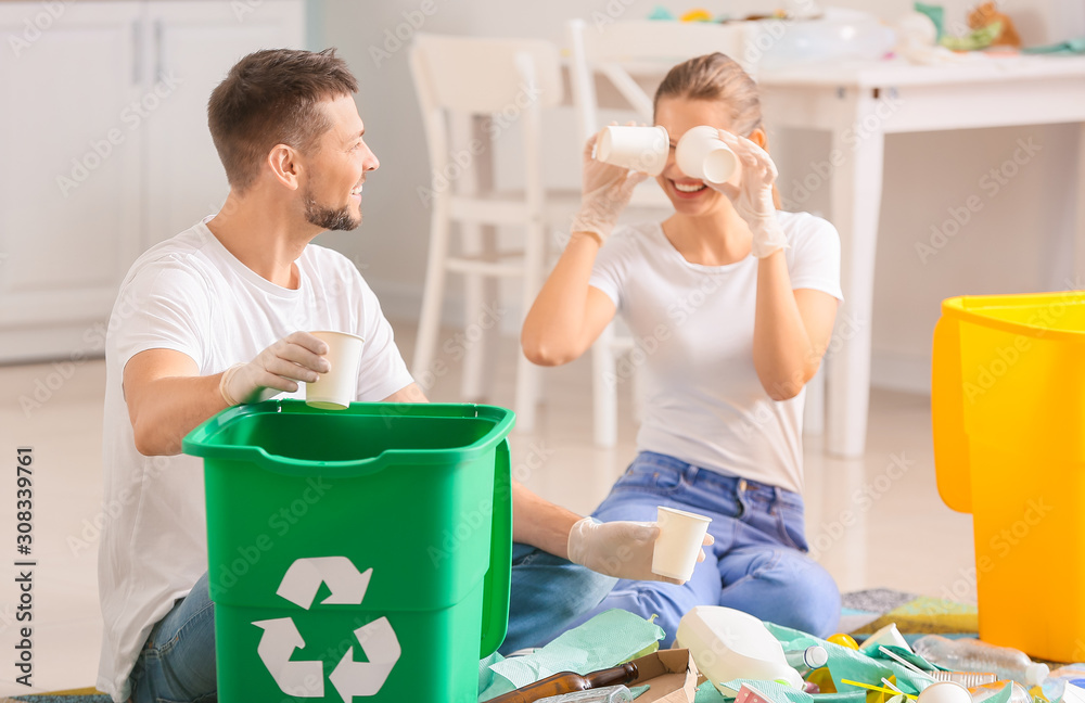 Funny couple sorting garbage at home. Concept of recycling