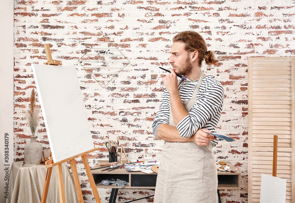 Young male artist painting at home