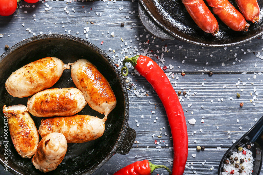 Frying pan with tasty grilled sausages on wooden background