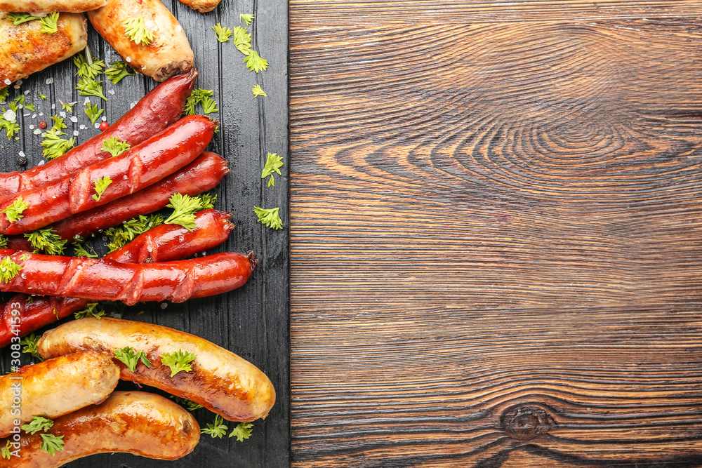 Tasty grilled sausages on wooden table