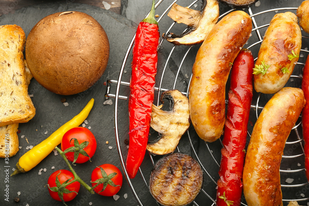 Tasty grilled sausages with vegetables on dark background