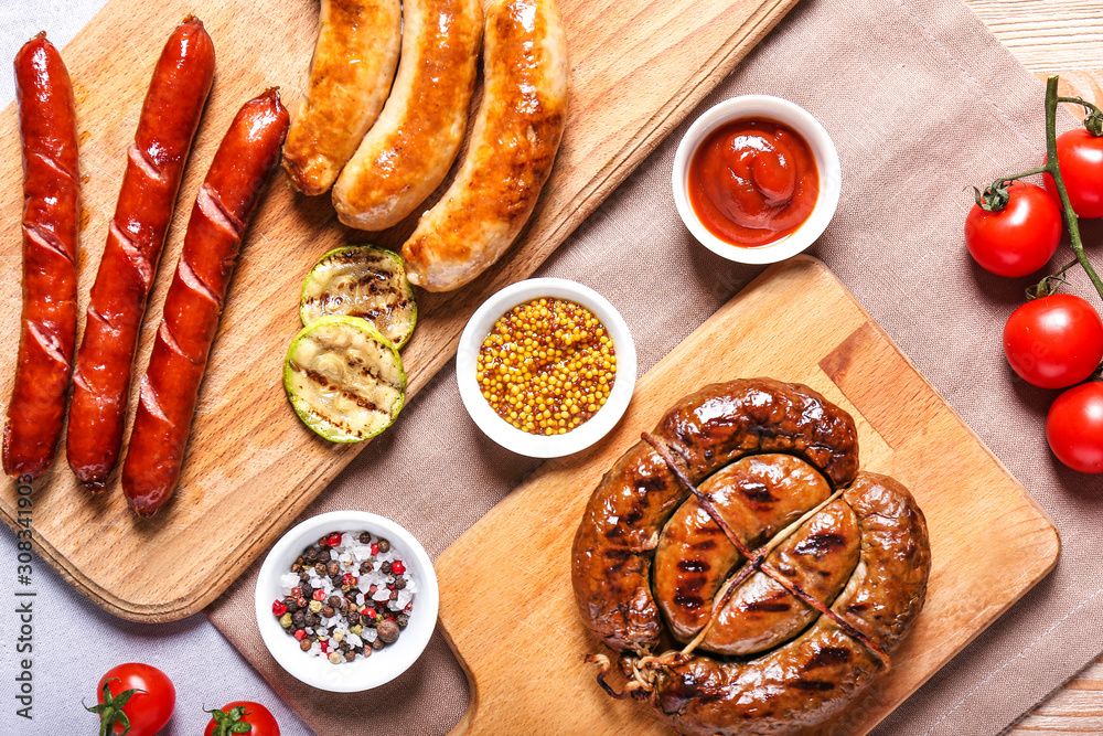 Wooden boards with tasty grilled sausages and sauces on table