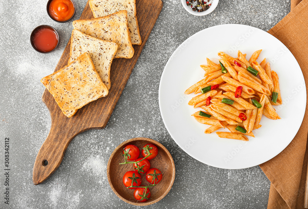 Plate with tasty pasta and bread on grey background