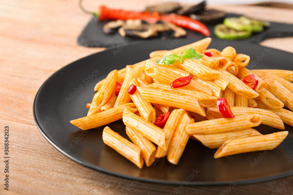 Plate with tasty pasta on wooden table, closeup