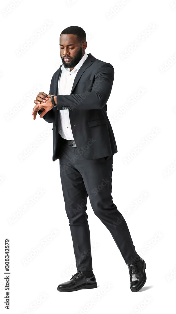 Stylish African-American man looking on his wrist watch against white background