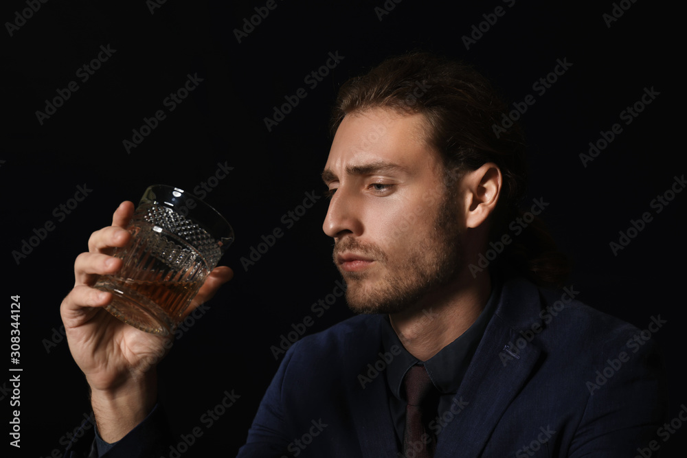 Portrait of handsome businessman with glass of alcohol on dark background