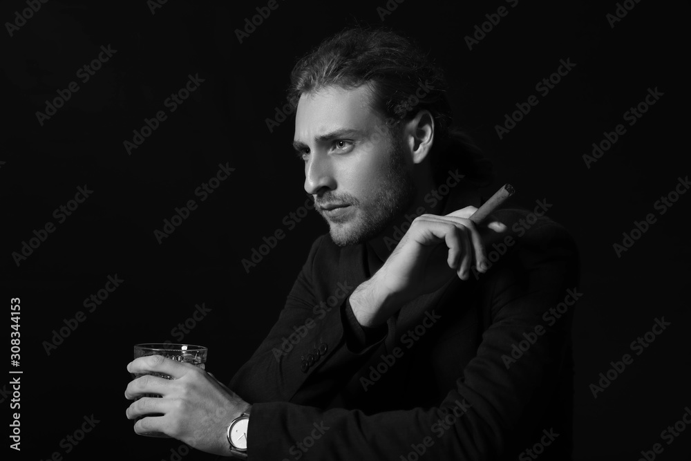 Black and white portrait of handsome businessman with alcohol and cigar on dark background