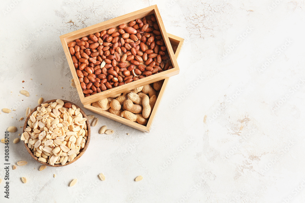 Boxes and bowl with peanuts on light background