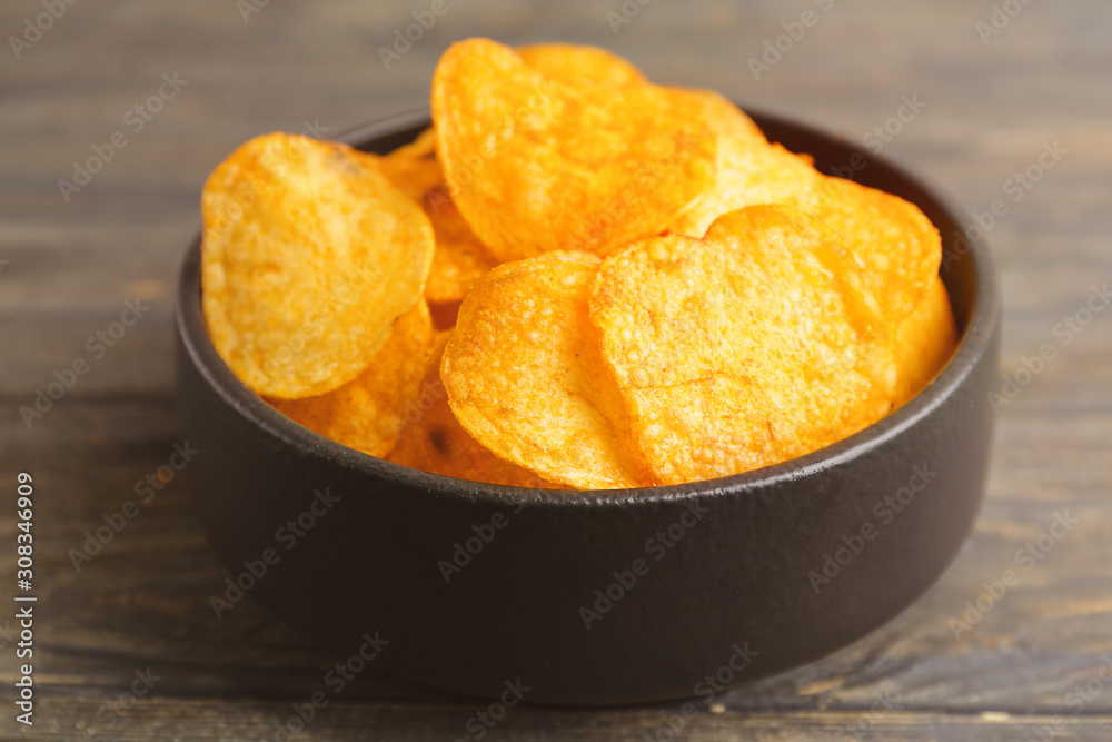 Bowl with tasty potato chips on table