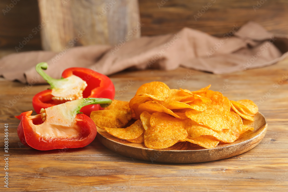 Plate with tasty potato chips and bell pepper on table