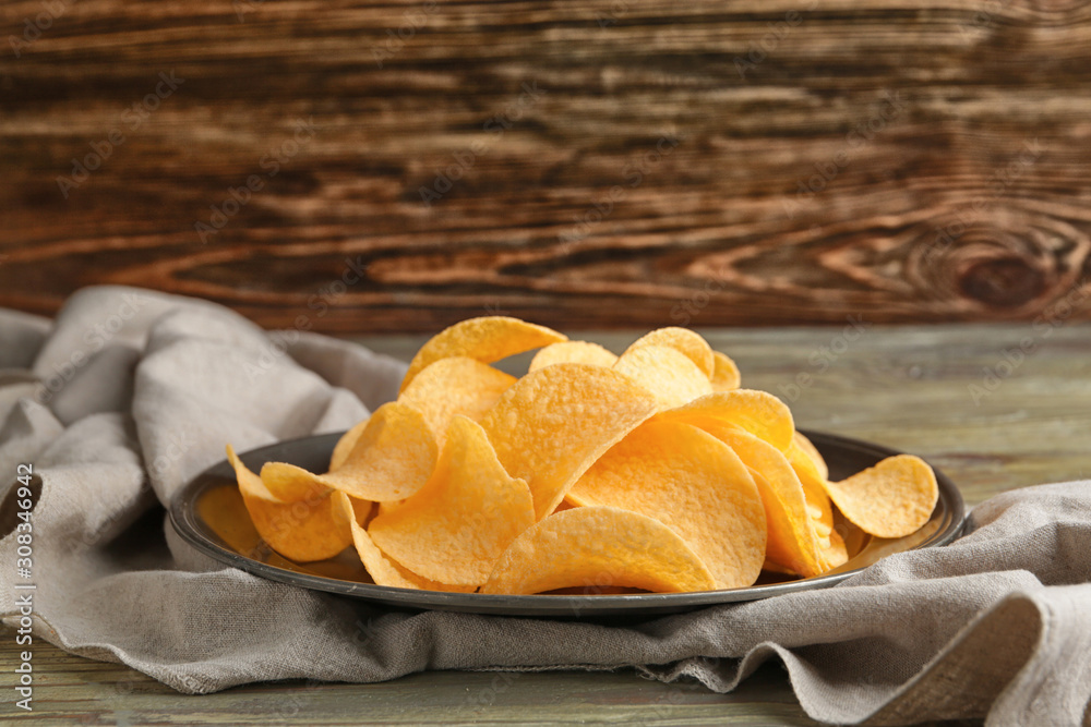 Plate with tasty potato chips on table