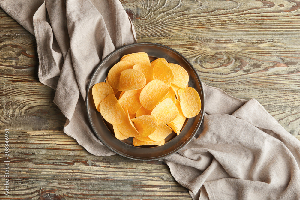 Plate with tasty potato chips on table