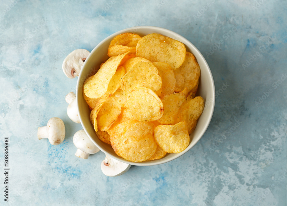 Bowl with tasty potato chips and mushrooms on table