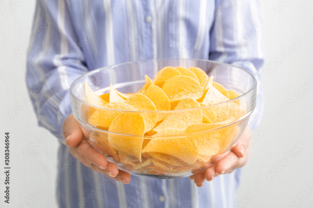 Woman with bowl of tasty potato chips, closeup