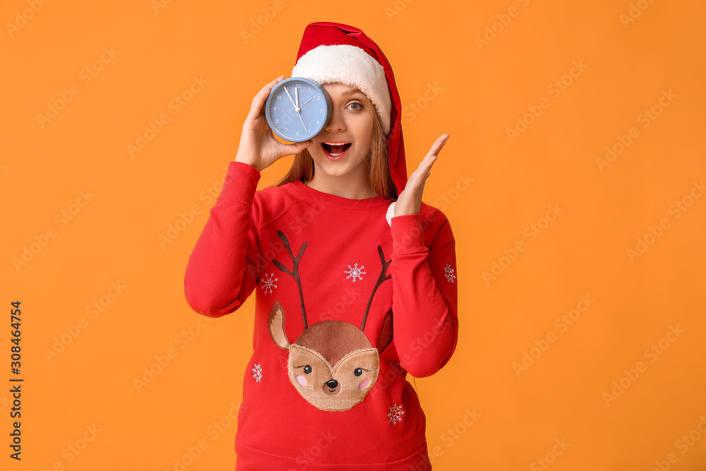 Young woman in Santa hat and with alarm clock on color background. Christmas countdown concept