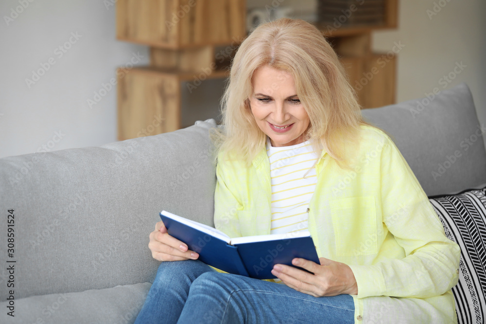 Beautiful mature woman reading book at home