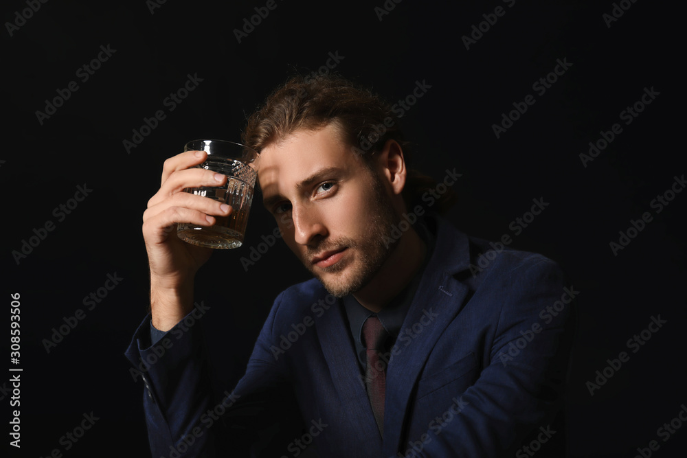 Portrait of handsome businessman with glass of alcohol on dark background