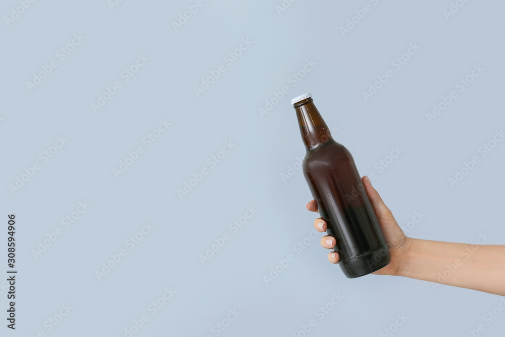 Hand with bottle of beer on grey background