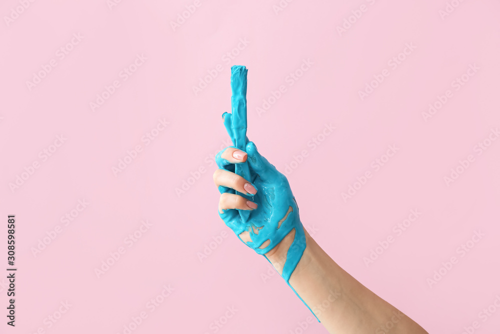 Hand of artist with brush on color background