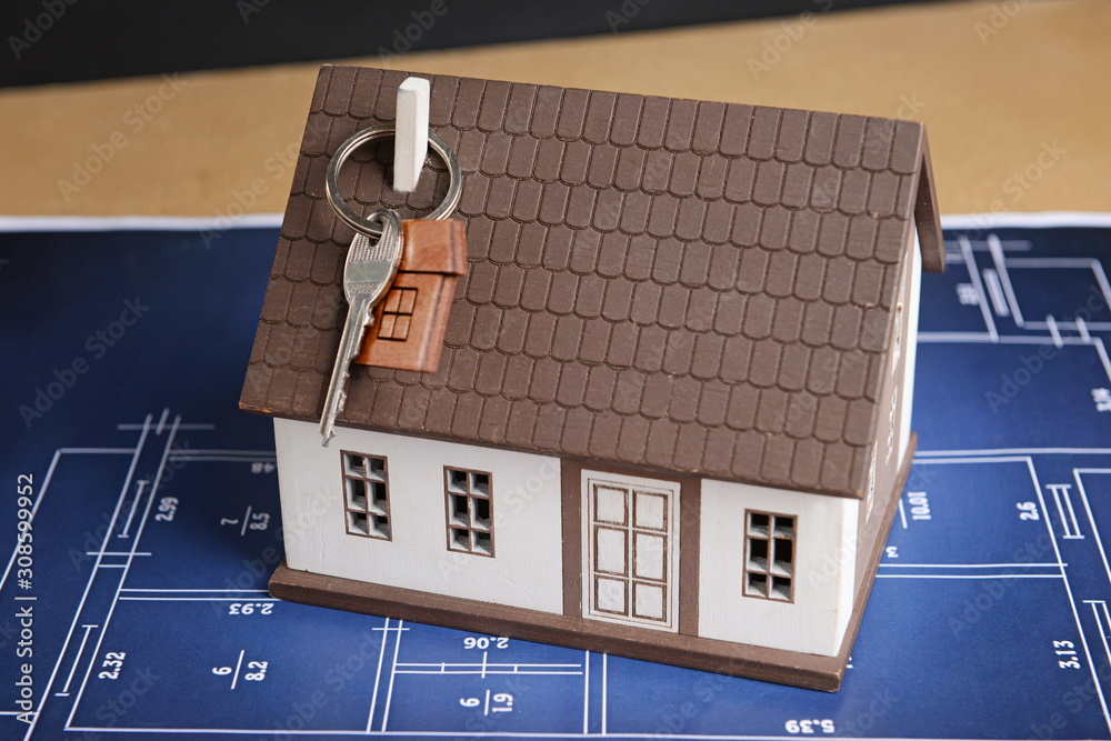 Model of house with key and drawing on table. Concept of buying new property