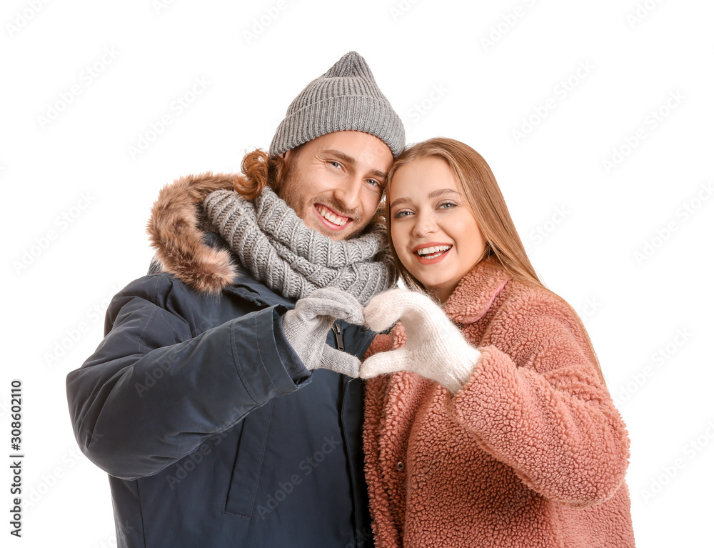 Happy couple in winter clothes making heart with their hands on white background